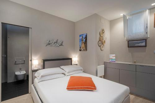 una camera da letto con un letto bianco e un cuscino arancione di Aurora 20 a Boccadasse by Wonderful Italy a Genova