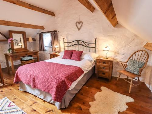 een slaapkamer met een groot bed en een houten vloer bij Y Bwthyn in Betws-y-coed