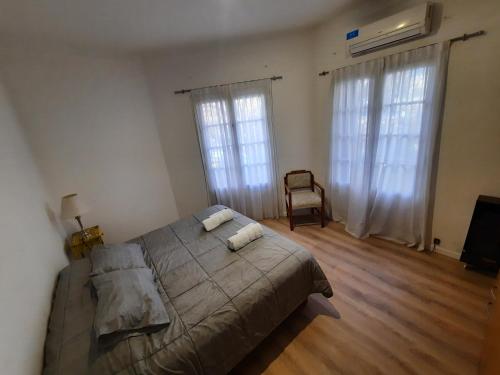 1 dormitorio con 1 cama, 1 silla y 2 ventanas en B&P Departamentos en Mendoza