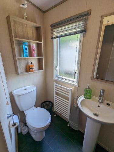 uma casa de banho com um WC, um lavatório e uma janela em Littlesea Caravan on a Fabulous elevated position Haven Weymouth em Weymouth