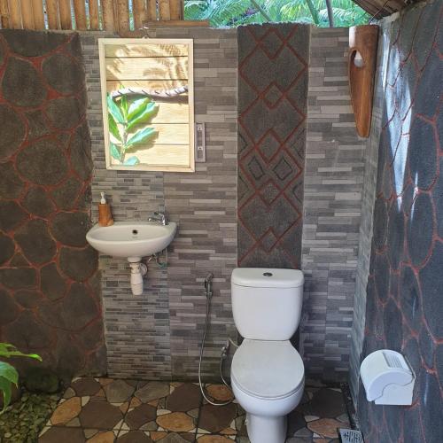 a bathroom with a toilet and a sink at Second Home Bungalows in Tetebatu