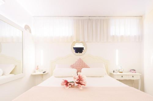 a white bedroom with a white bed with pink flowers on it at Le Monachelle Luxury in Eboli