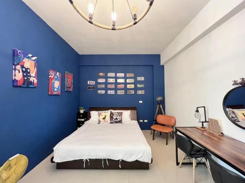 Dormitorio azul con cama y escritorio en Brother Homestay, en Taitung