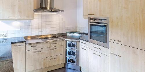 a kitchen with wooden cabinets and a stove top oven at Brugghof Apartment Brugg in Madonna