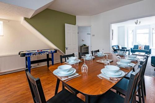 a dining room with a large wooden table with chairs at Touchwood House Llandudno in Llandudno