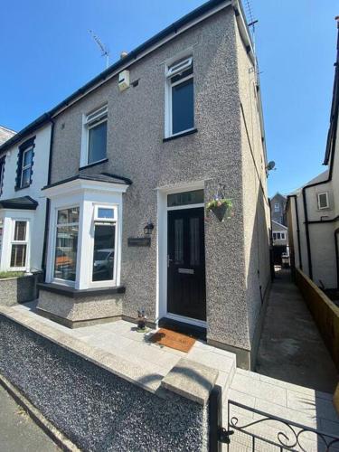 a brick house with a black door on a street at Touchwood House Llandudno in Llandudno
