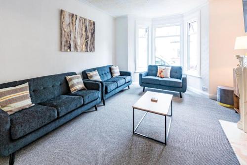 uma sala de estar com dois sofás azuis e uma mesa em Touchwood House Llandudno em Llandudno