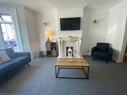 a living room with a couch and a table and a fireplace at Touchwood House Llandudno in Llandudno