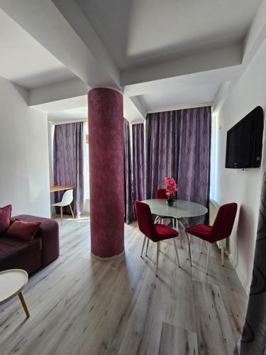 a living room with a table and red chairs at Gabizz Apartments in Constanţa