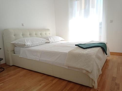 a bedroom with a white bed with a large window at City Apartment Dora in Makarska