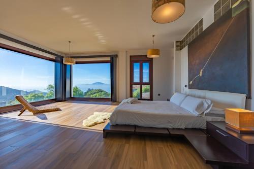 a bedroom with a large bed and large windows at Livingtarifa - Casa Los Helechos in El Bujeo