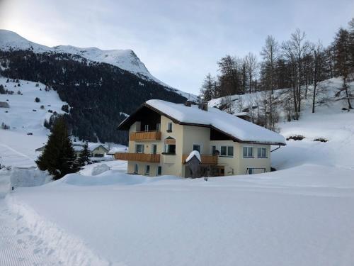 a house in the snow in the mountains at Garni Schanz in Resia