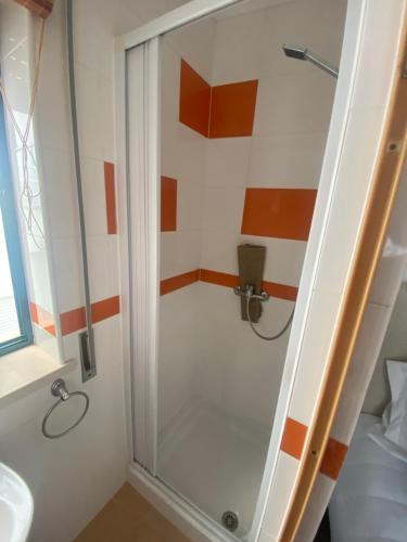 a shower with a glass door in a bathroom at Casa Prédio triplex - Faneca Apartamentos in Nazaré