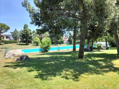 una piscina en un patio con árboles y césped en El Coqueto de Segovia, en El Espinar