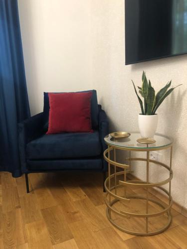 a blue couch with a red pillow and a table at Studio 106 Apartment in Palić