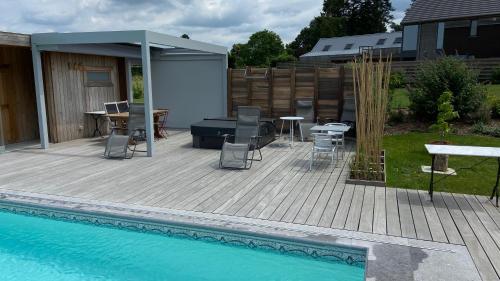 Un patio con mesa y sillas junto a una piscina. en B&B Les Autres Sens, en Villers-la-Ville