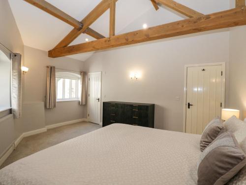 um quarto com uma cama branca e vigas de madeira em Lakeside Mill Cottage em Stroud