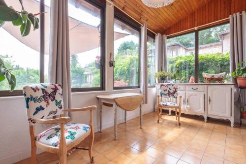 une pièce avec une table et deux chaises et des fenêtres dans l'établissement La maison du lac du Grobon, à Châtillon-sur-Chalaronne