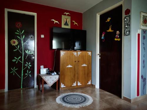 a living room with a tv on a red wall at Jenny's House in Yerakiní