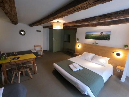 um quarto com uma cama, uma secretária e uma mesa em La Maison - Hôtel & Gîte em Laguiole