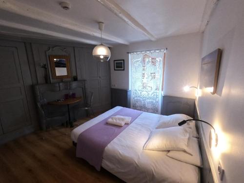 a bedroom with a bed with white sheets and a window at La Maison - Hôtel & Gîte in Laguiole