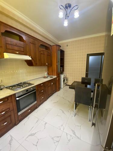 uma cozinha com armários de madeira, uma mesa e um fogão em ЖК Томирис 2 комнатная квартира em Atyraū