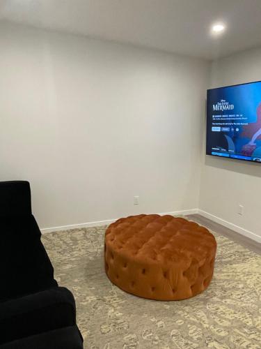 a large brown ottoman in a room with a tv at Grande Villa in Calgary