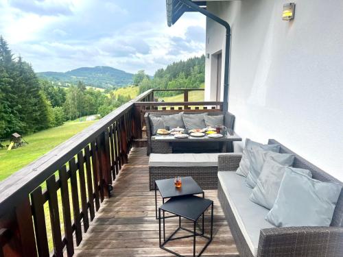 een balkon met banken en een tafel met borden. bij Premium Apartment Rokytnice in Rokytnice nad Jizerou