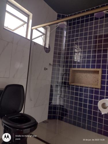 a bathroom with a toilet and a blue tiled wall at Recanto Serra Monte in Caparaó Velho