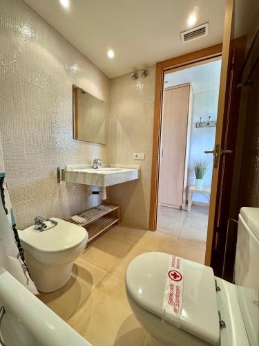 a bathroom with a white toilet and a sink at Apartamento en l'Ampolla con piscina in L'Ampolla