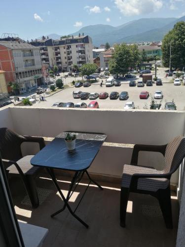 a table and chairs on a balcony with a parking lot at STE-FI APARTMANS in Gostivar