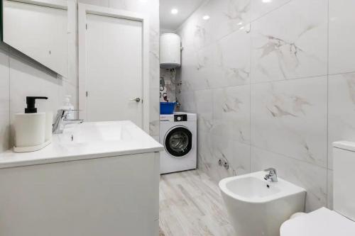 y baño blanco con lavabo y lavadora. en Luxury Flat, few minutes from Fanabe Beach! en Adeje