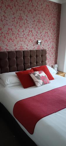 a large bed with red and white pillows on it at Lawnswood Guest House in Torquay