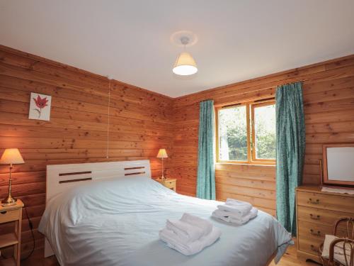 sypialnia z drewnianymi ścianami i łóżkiem z ręcznikami w obiekcie Dailfearn Chalet w mieście Stromeferry