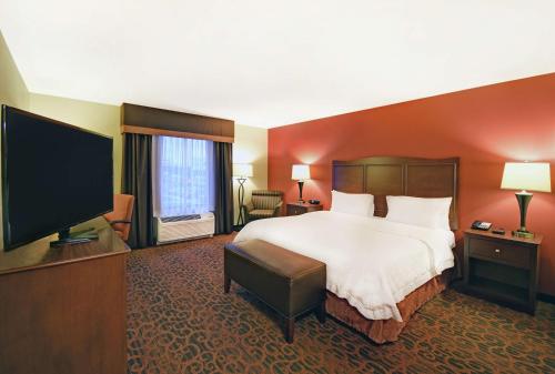 a hotel room with a bed and a flat screen tv at Hampton Inn Beloit in Beloit