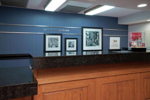 a blue wall with framed pictures on a counter at Hampton Inn Jackson in Jackson
