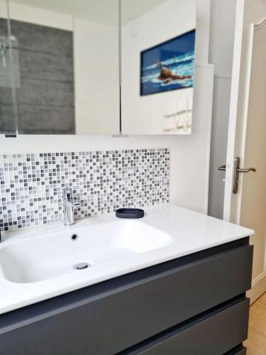 une salle de bain avec un lavabo blanc et un miroir dans l'établissement Appartement spacieux centre ville et plage à pied, à Concarneau