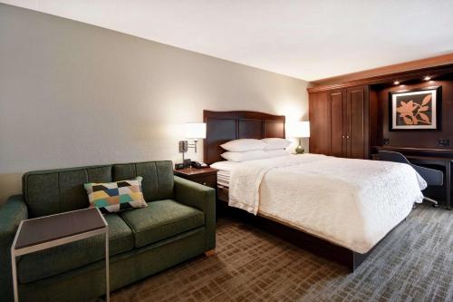 a hotel room with a bed and a couch at Hampton Inn Overland Park in Overland Park
