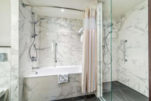 a bathroom with a shower and a tub and a sink at Hilton Garden Inn Krakow Airport in Krakow