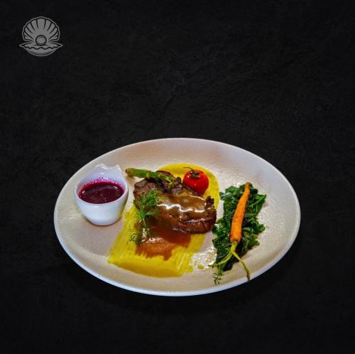 a plate of food with meat and vegetables on a table at Perla e Dumrese, Bar-Restaurant-Hotel in Belsh