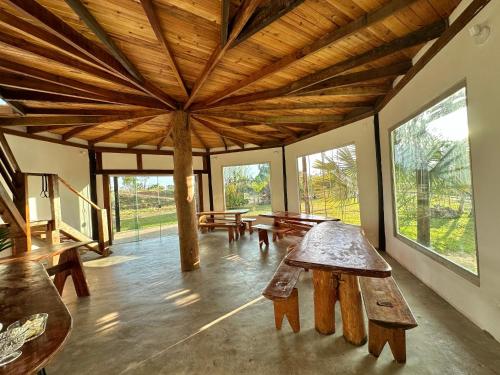 um quarto com mesas e bancos de madeira e janelas em Pousada/Camping Mirante Serrano em Alto Paraíso de Goiás