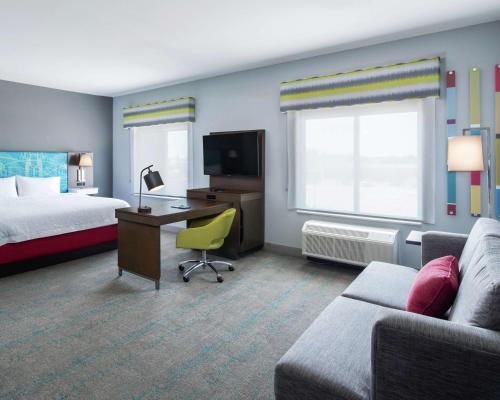 ein Hotelzimmer mit einem Bett, einem Schreibtisch und einem Sofa in der Unterkunft Hampton Inn & Suites Lubbock in Lubbock