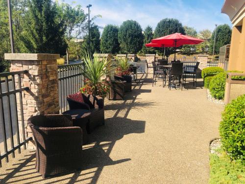 a patio with chairs and tables and a red umbrella at Hampton Inn Lewisburg in Lewisburg