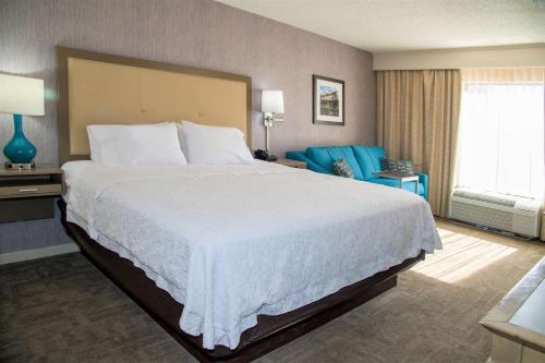 una habitación de hotel con una cama grande y sillas azules en Hampton Inn Lewisburg, en Lewisburg