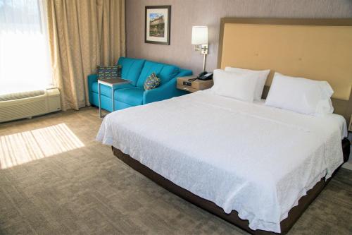a hotel room with a large bed and a blue couch at Hampton Inn Lewisburg in Lewisburg