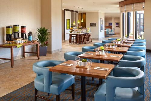 a restaurant with wooden tables and blue chairs at Hilton Garden Inn Los Angeles/Redondo Beach in Redondo Beach