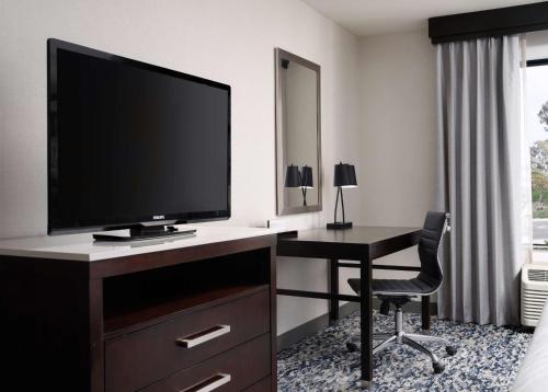 a room with a desk with a television and a chair at Hilton Garden Inn Los Angeles/Redondo Beach in Redondo Beach