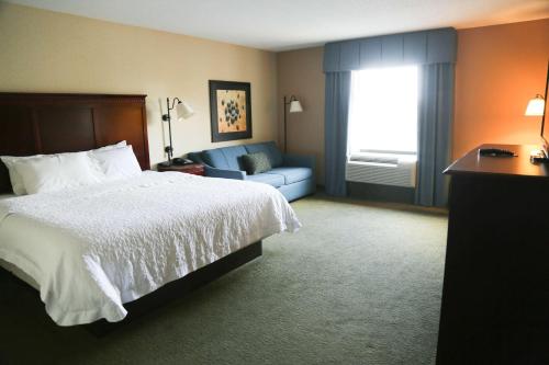 a hotel room with a bed and a blue couch at Hampton Inn Morehead in Morehead