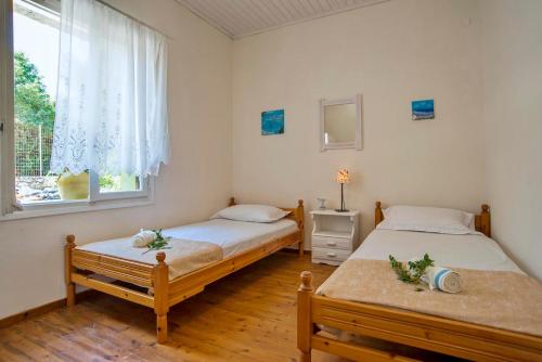 two beds in a room with a window at Agnis House in Antípaxos