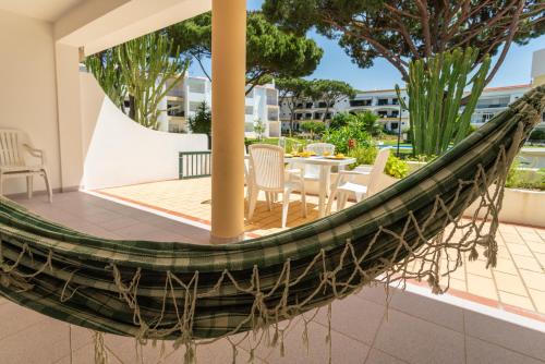 a hammock on a patio with a table and chairs at Host Wise - Amazing Sunny Flat - Swimming Pool & Terrace in Vilamoura